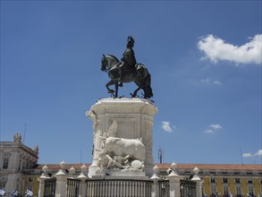 An equestrian statue of a king on a monument, under a blue sky with a few clouds, Lisbon, portugal
