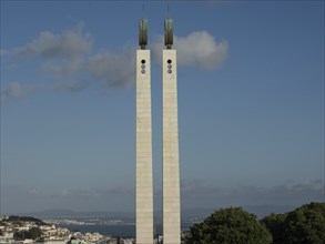 Two identical towers rise into the sky above a city with many trees, Lisbon, Portugal, Europe