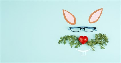 Easter rabbit face with a heart shaped nose, whiskers from carrot leaves and eyeglasse, holiday