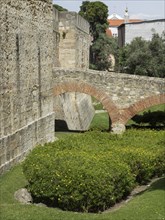 Stone archway in the garden of a medieval building, surrounded by green bushes, Lisbon, portugal