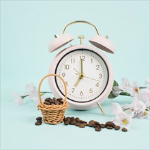 Wicker basket with roasted coffee beans, an alarm clock and cherry blossom, wake up in the morning,