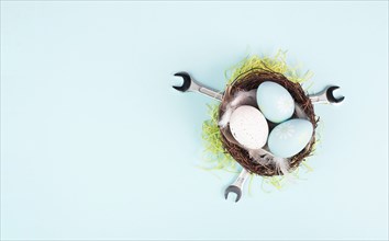 Easter eggs in a bird nest, wrenches and green grass, holiday greeting card with repair tools,