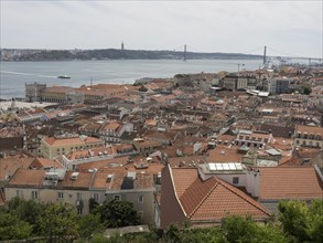 View of a city with red roofs, a river and a bridge in the background, Lisbon, portugal