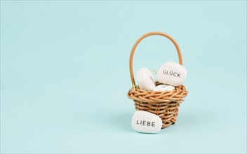 Basket with white pebbles, words like luck and love standing in german language on the stones, gift
