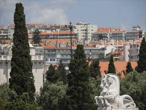 Cityscape with red roofs, trees and a white monument under a cloudy sky, Lisbon, portugal