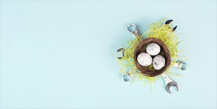 Easter eggs in a bird nest, wrenches and green grass, holiday greeting card with repair tools,
