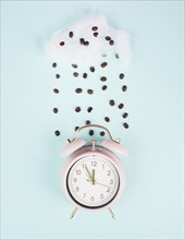 Wake up, time for a coffee break, alarm clock with roasted beans raining from a cloud