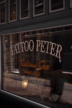 A traditional tattoo shop with a retro sign and nostalgic atmosphere, seen from the outside,