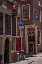Old town centre with cobblestones, red brick buildings, signs and narrow streets, Amsterdam,