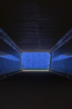A tunnel with blue lighting ends in an exit with a water landscape and the inscription Waterland,