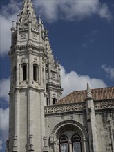 Gothic architecture of a cathedral with striking towers in front of a partly cloudy sky, Lisbon,