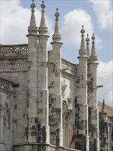 Detail of a gothic church façade with stone ornaments and towers under a cloudy sky, Lisbon,
