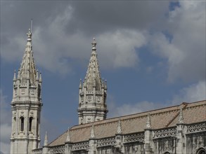 Two gothic steeples of a stone church under a cloudy blue sky, Lisbon, portugal