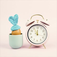 Cute easter bunny or rabbit in a cup with an alarm clock, spring holiday, greeting card