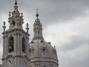 Baroque church tower and dome of a white church in front of a cloudy sky, Lisbon, portugal
