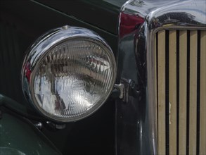Close-up of a headlight of a green vintage car with chrome accents, winterswijk, gelderland, the