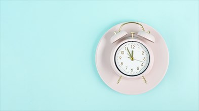 Alarm clock on a plate in old retro style, pastel color, time for a break, having lunch