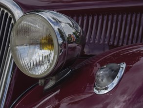 Headlights of a red vintage car that conveys a sense of nostalgia and classic design, winterswijk,