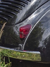 Detailed view of a black vintage car, showing the rear light and reflective chrome parts in
