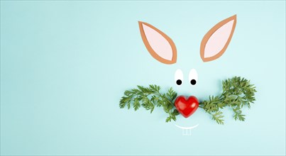 Easter bunny face with a heart shaped nose and whiskers from carrot leaves, holiday greeting card,