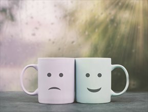 Happy and sad face, cup couple on a window ledge cuddle each other, hot drink on a rainy day, love,