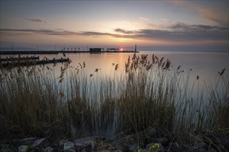 Sunrise on the shore and harbour of a lake in summer. Colourful sky with a wide view of the horiont