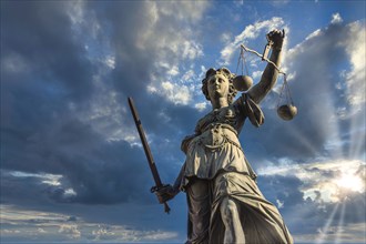 Justitia monument in Frankfurt roemerberg during sunset with cloudy sky, low angle