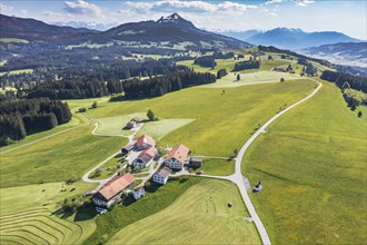 Aerial view of rural road in blomstering meadows, large farm Gereute with small chapel, mountain