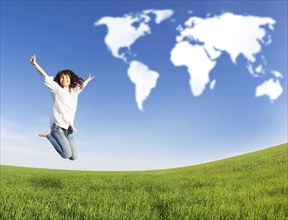 Happy woman jumping in green field against blue sky. Summer vacation concept