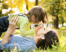 Happy family lying on grass in autumn park