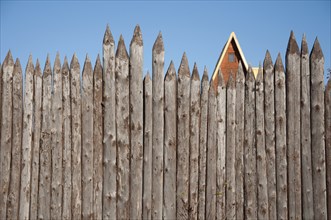 The wooden fence of sharpened logs timber