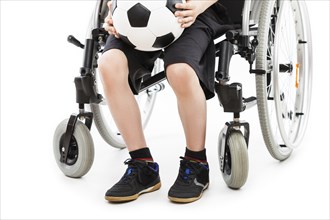 Invalid or disabled child boy sitting on wheelchair hand holding soccer sport ball white isolated