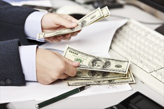 Working business man hand counting or calculating dollar currency at office workplace