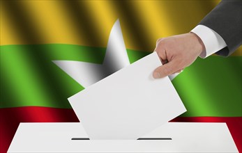 The Myanmar flag and the hand with the bulletin about the ballot box