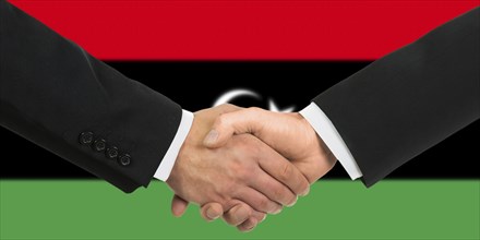 The Libyan flag and business handshake