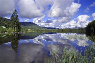 Tranquillity of a mirror-smooth lake surrounded by mountains and cloudy skies, Voss, Norway, Europe