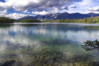 Crystal clear lake surrounded by mountains, clouds and forests with a clear sky, Jasper, Jasper