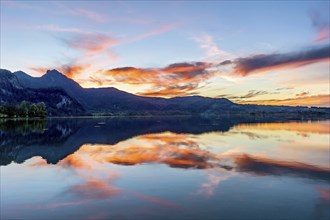 Lake Kochel with reflection of sun and clouds at sunset, calm water, behind the mountains Stein,