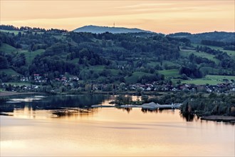 View of the Lake Kochel calm water, warm evening light, sunset, sand and gravel works Schlehdorf,