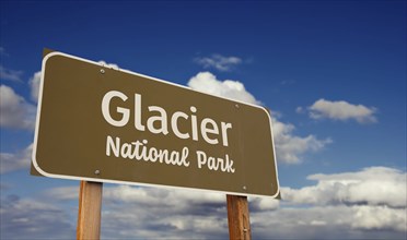 Glacier national park (montana) road sign against blue sky and clouds