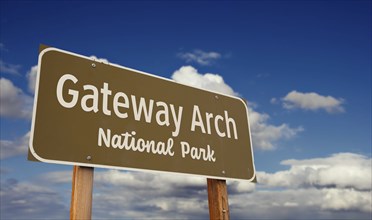 Gateway arch national park (missouri) road sign against blue sky and clouds