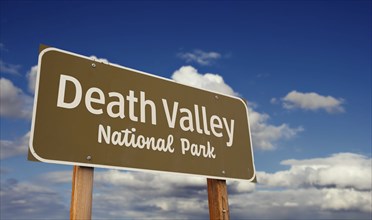 Death valley national park (california, nevada) road sign against blue sky and clouds