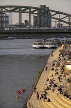 Rhine promenade, Rhine boulevard, on the Deutz bank, people sitting in the spring sun on the Rhine,