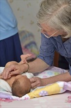 A senior midwife checks a newborn baby with her mother