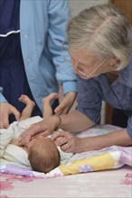 A senior midwife checks a newborn baby with her mother