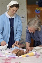 A senior midwife checks a newborn baby with her mother