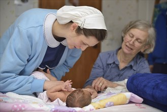 A senior midwife checks a newborn baby with her mother