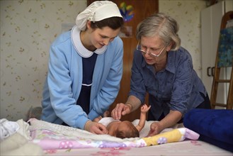 A senior midwife checks a newborn baby with her mother