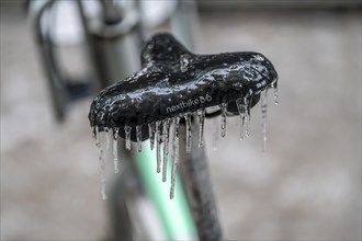 Freezing rain, icy saddle of a rental bike, after freezing rain, in the city centre of Frankfurt,