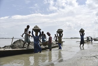 Labourer carries extracted sand from Beki River, in Barpeta district in Assam, India on Sunday